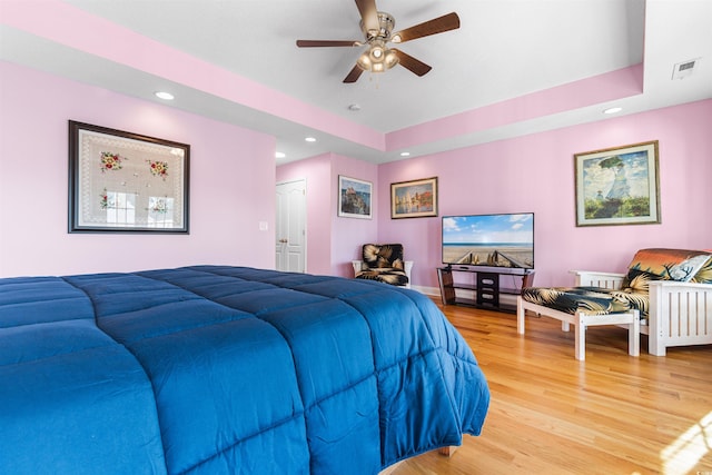 bedroom featuring a closet, ceiling fan, a raised ceiling, and light hardwood / wood-style flooring