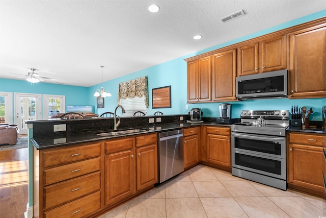 kitchen with sink, appliances with stainless steel finishes, kitchen peninsula, and dark stone counters