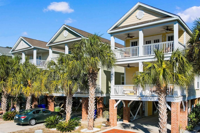 coastal inspired home featuring covered porch, ceiling fan, a balcony, and a carport