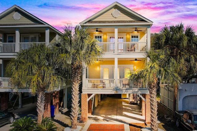 back house at dusk featuring a porch, french doors, ceiling fan, a balcony, and a carport