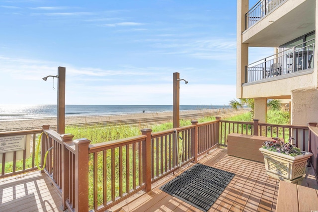 wooden deck featuring a water view and a beach view