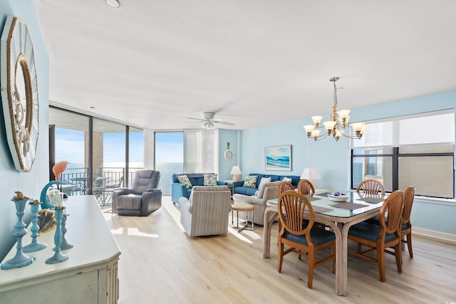 dining space with floor to ceiling windows, ceiling fan with notable chandelier, and light wood-type flooring