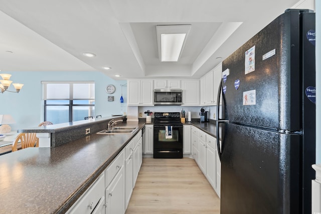 kitchen featuring white cabinetry, sink, a tray ceiling, and black appliances