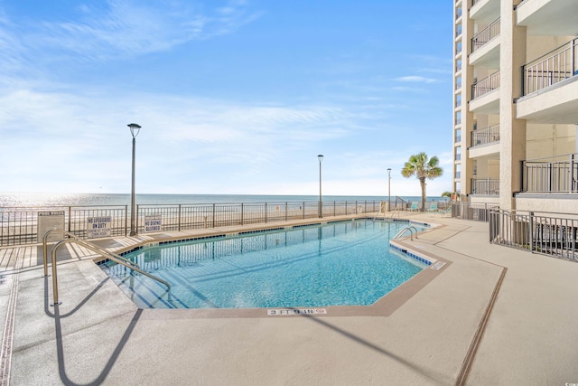 view of swimming pool featuring a water view and a patio