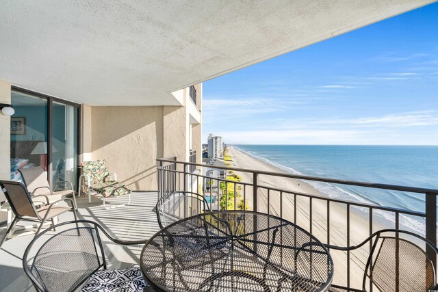 balcony featuring a view of the beach and a water view