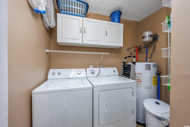 laundry room featuring cabinets, washing machine and dryer, water heater, and a textured ceiling