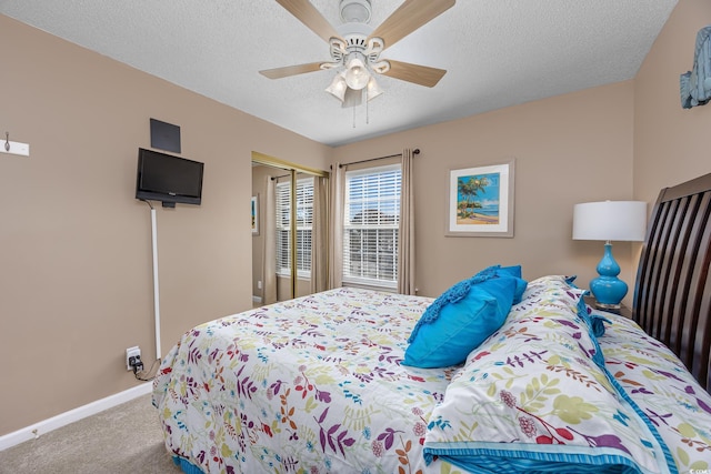 bedroom with a textured ceiling, light colored carpet, a closet, and ceiling fan