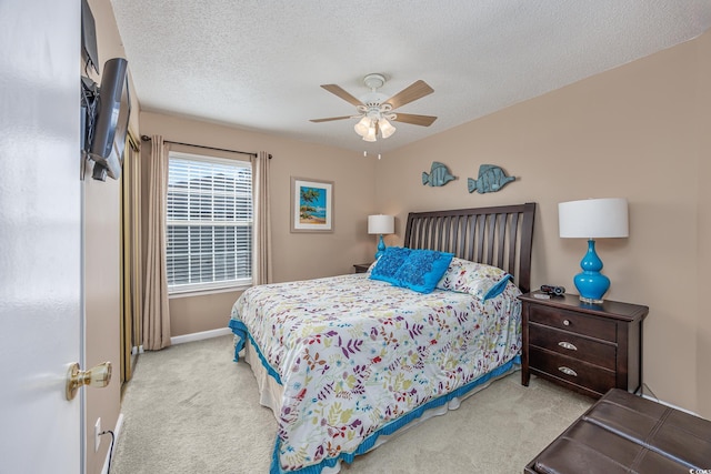 bedroom featuring light carpet, a textured ceiling, and ceiling fan