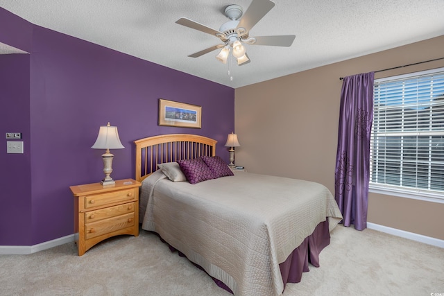 bedroom featuring light carpet, a textured ceiling, and ceiling fan