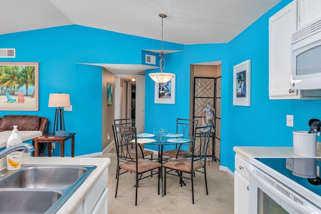 carpeted dining area with sink, vaulted ceiling, and a textured ceiling