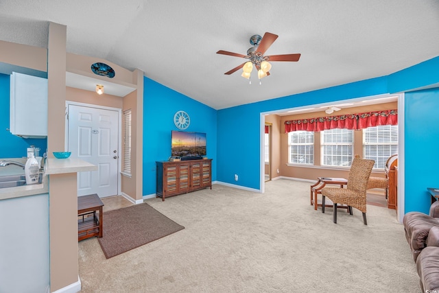 living room featuring lofted ceiling, light carpet, a textured ceiling, and ceiling fan