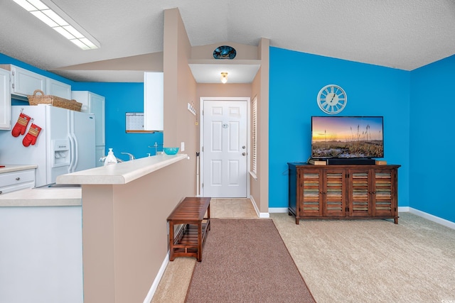 kitchen with vaulted ceiling, white cabinetry, white refrigerator with ice dispenser, light colored carpet, and kitchen peninsula