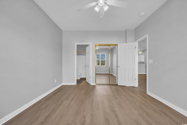 washroom featuring electric water heater, baseboards, stacked washer / dryer, laundry area, and wood finished floors