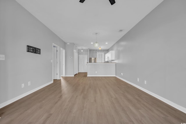 unfurnished living room featuring baseboards, ceiling fan, and wood finished floors