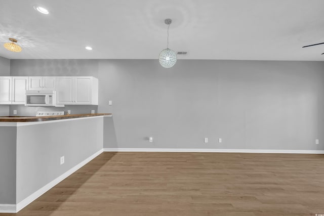 901 W Port Dr Unit 1706, North Myrtle Beach, SC 29582 - kitchen with light wood-style flooring, recessed lighting, baseboards, white microwave, and white cabinets
