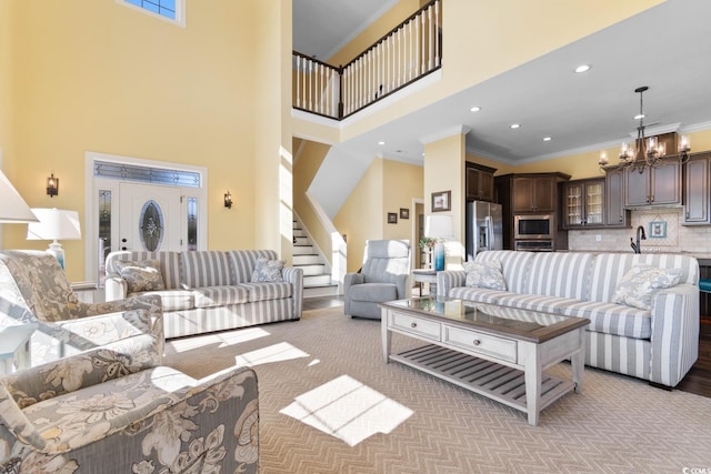 living room featuring an inviting chandelier, a towering ceiling, and ornamental molding