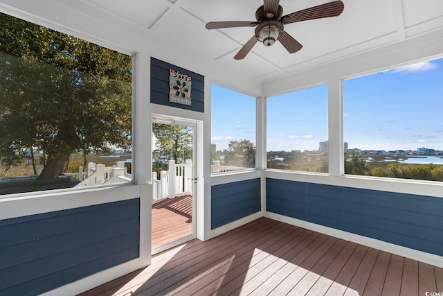 unfurnished sunroom featuring ceiling fan and a water view