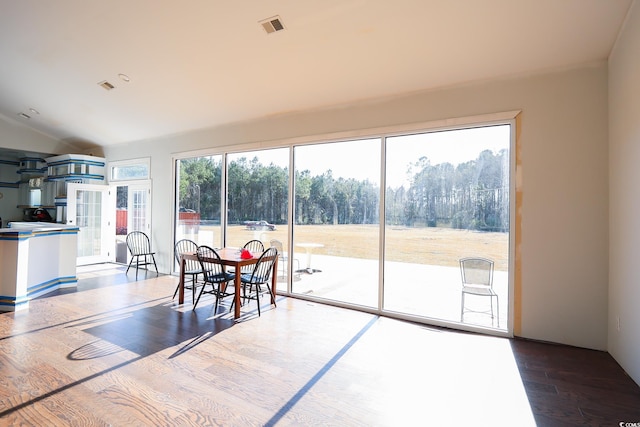 dining room with visible vents, lofted ceiling, and wood finished floors