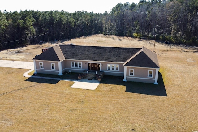 view of front of property featuring a front lawn and a forest view