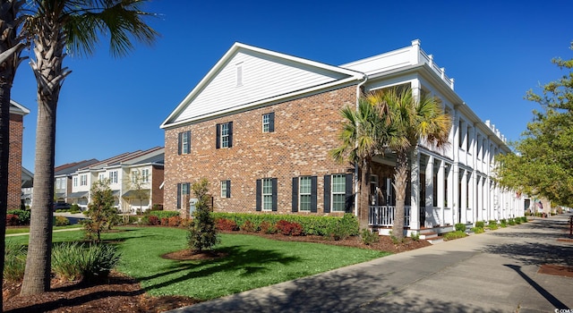 view of side of property featuring a residential view, brick siding, and a lawn