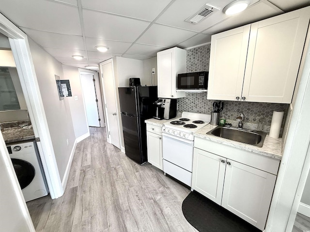 kitchen with washer / dryer, sink, white cabinetry, black appliances, and a drop ceiling