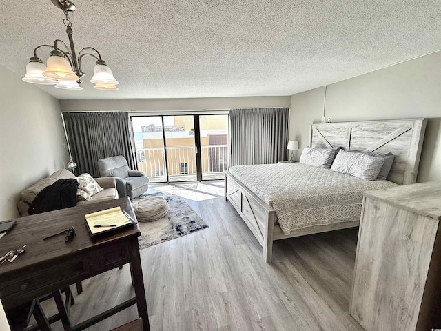 bedroom featuring a textured ceiling, wood-type flooring, access to outside, and an inviting chandelier