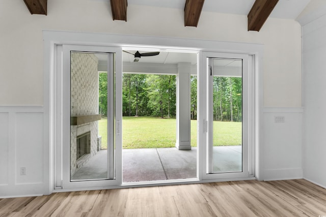7053 Byrnes Ln, Myrtle Beach, SC 29588 - doorway featuring a large fireplace, a decorative wall, beam ceiling, wood finished floors, and wainscoting