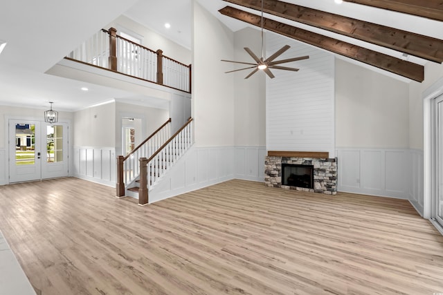 7053 Byrnes Ln, Myrtle Beach, SC 29588 - unfurnished living room with stairs, a decorative wall, light wood-style floors, a fireplace, and high vaulted ceiling