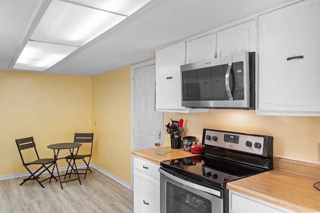 1020 Thomas Ave, North Myrtle Beach, SC 29582 - kitchen with stainless steel appliances, light wood-style floors, white cabinets, and baseboards