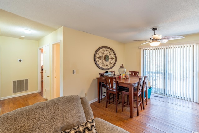 dining room featuring ceiling fan, a textured ceiling, and light hardwood / wood-style floors