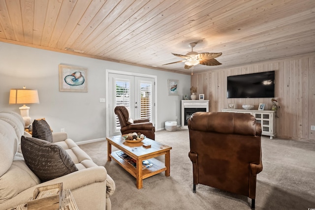 carpeted living room featuring french doors, ornamental molding, wood ceiling, and wooden walls