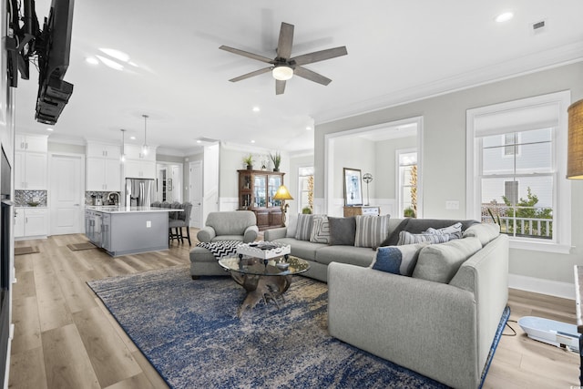 living room featuring crown molding, ceiling fan, sink, and light hardwood / wood-style flooring