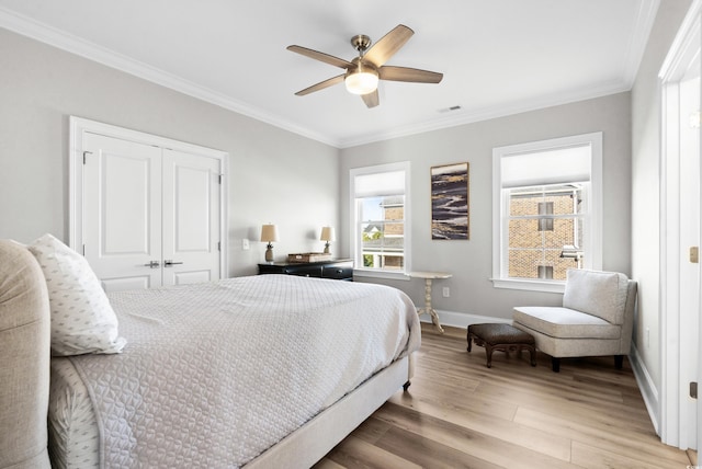 bedroom featuring crown molding, ceiling fan, wood-type flooring, and a closet