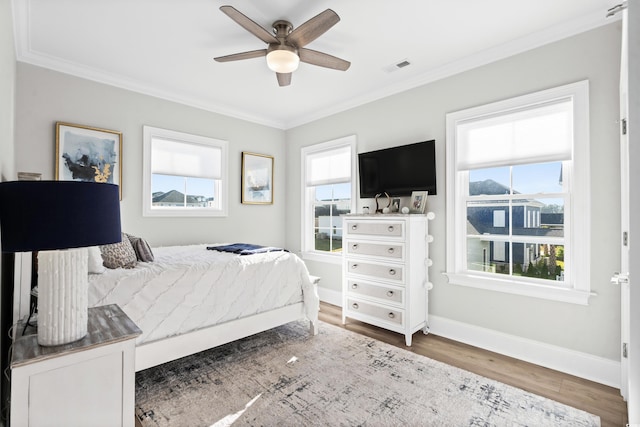 bedroom with multiple windows, ornamental molding, hardwood / wood-style floors, and ceiling fan