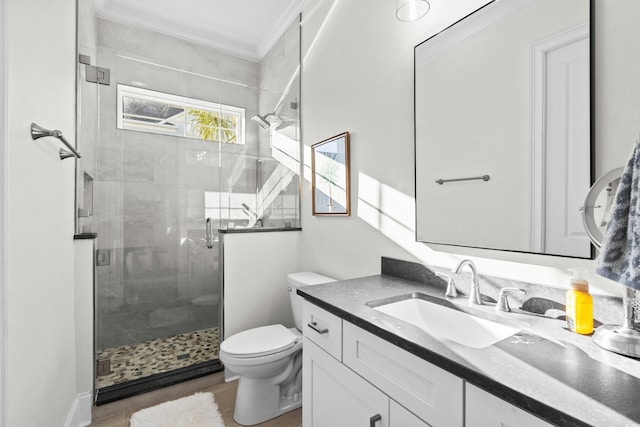 bathroom featuring a shower with door, vanity, ornamental molding, and toilet