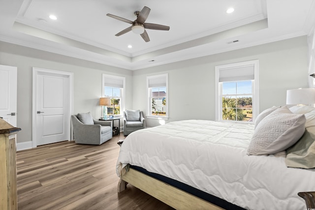 bedroom with hardwood / wood-style flooring, ornamental molding, a raised ceiling, and ceiling fan