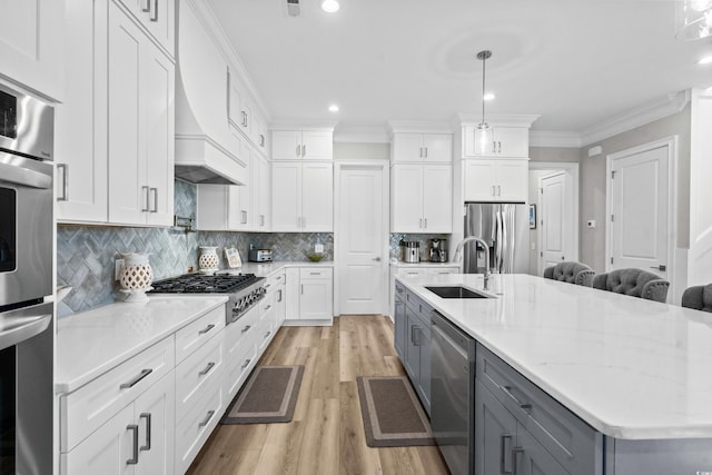 kitchen featuring white cabinetry, sink, pendant lighting, and stainless steel appliances