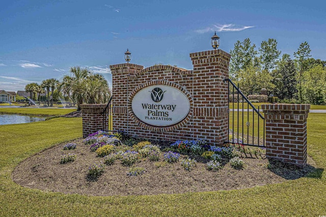 community / neighborhood sign featuring a water view and a lawn