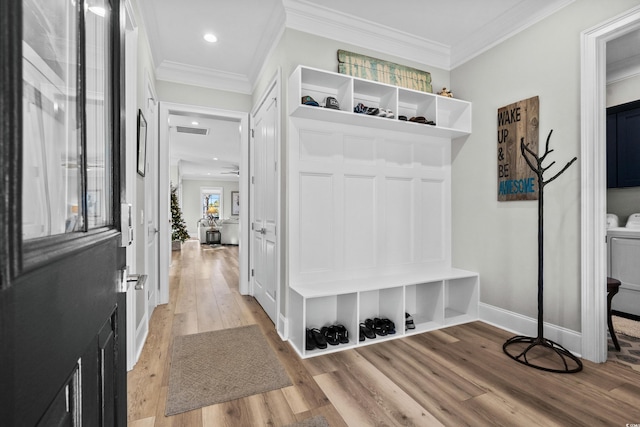 mudroom with crown molding, light hardwood / wood-style floors, and washing machine and dryer