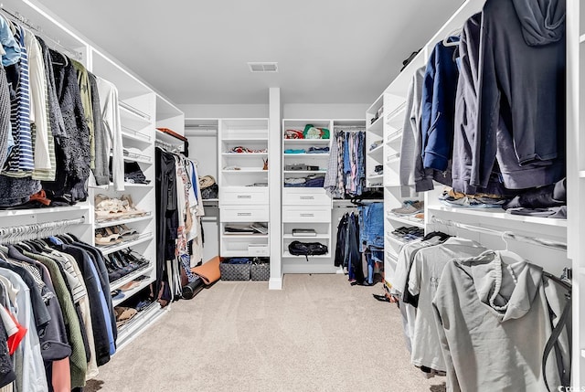 walk in closet featuring light colored carpet