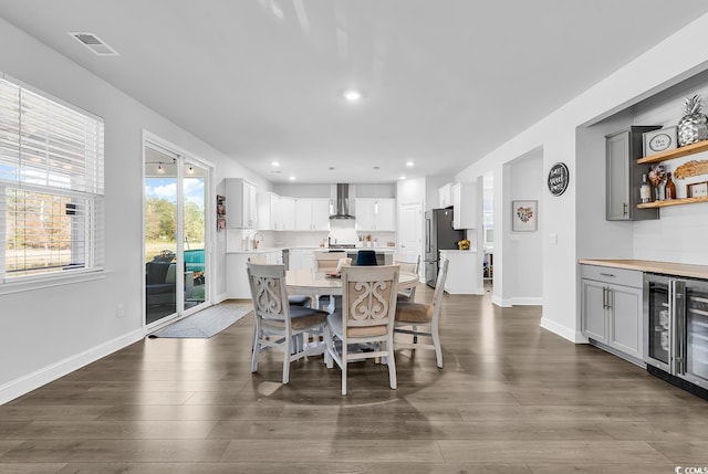 dining room with dark hardwood / wood-style flooring, beverage cooler, and bar area