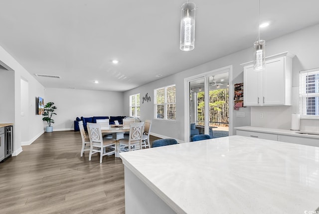 kitchen with hardwood / wood-style floors, decorative light fixtures, and white cabinets