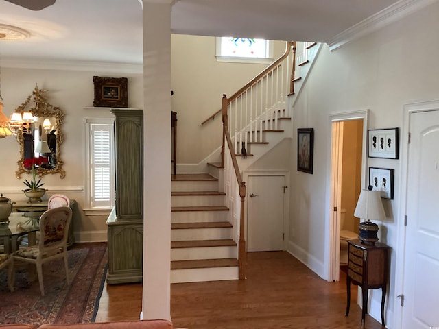 stairs featuring crown molding, wood-type flooring, and a wealth of natural light