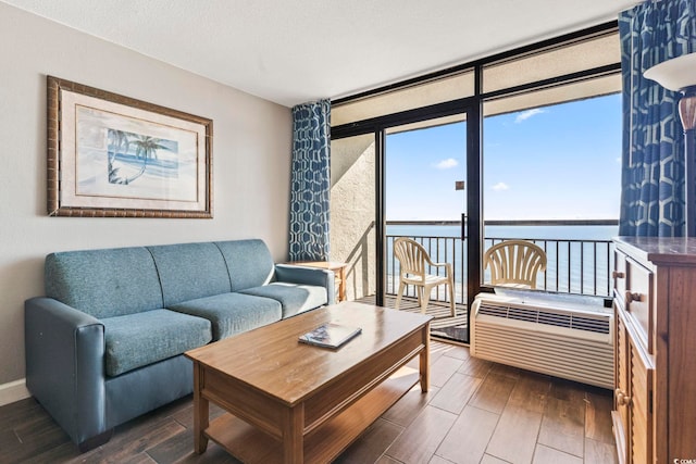 living room featuring expansive windows, a water view, a wealth of natural light, and a wall unit AC