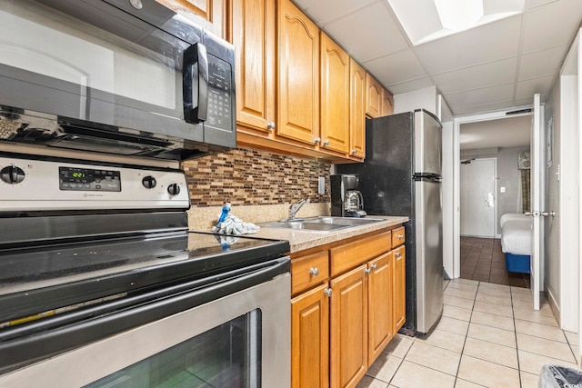 kitchen featuring sink, backsplash, stainless steel appliances, and light tile patterned floors