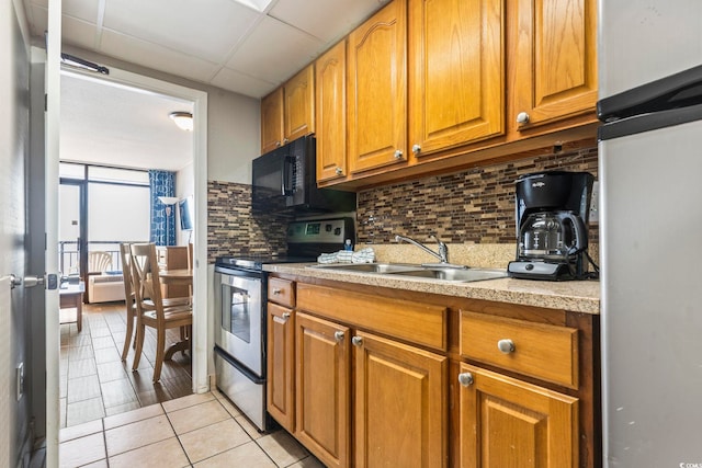 kitchen featuring sink, stainless steel appliances, tasteful backsplash, light tile patterned flooring, and a drop ceiling