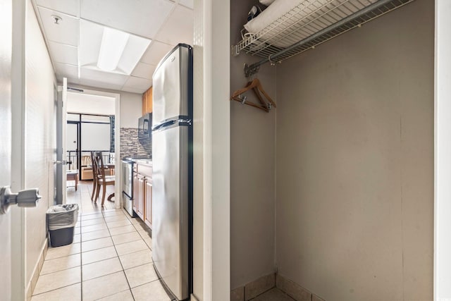 interior space with light tile patterned flooring, appliances with stainless steel finishes, and backsplash