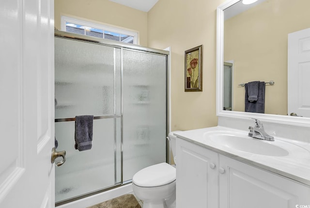 bathroom featuring vanity, toilet, and a shower with shower door