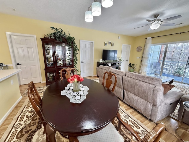 dining room with ceiling fan, a textured ceiling, and light wood-type flooring