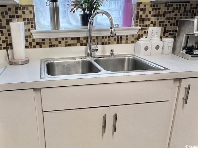 details with sink, white cabinets, and backsplash